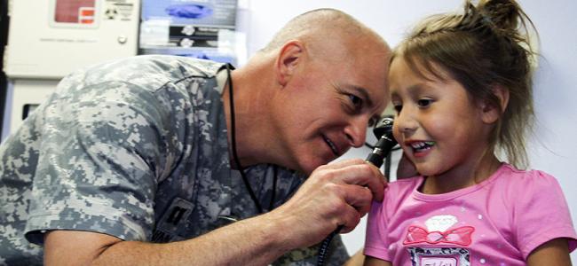 Army doctor examining little girl's ears